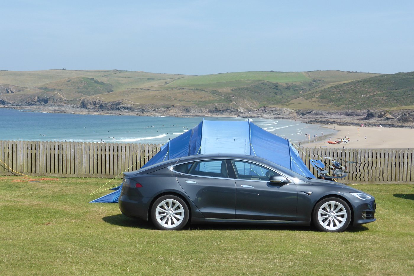 Una Tesla con la tenda agganciata, in campeggio davanti al mare.